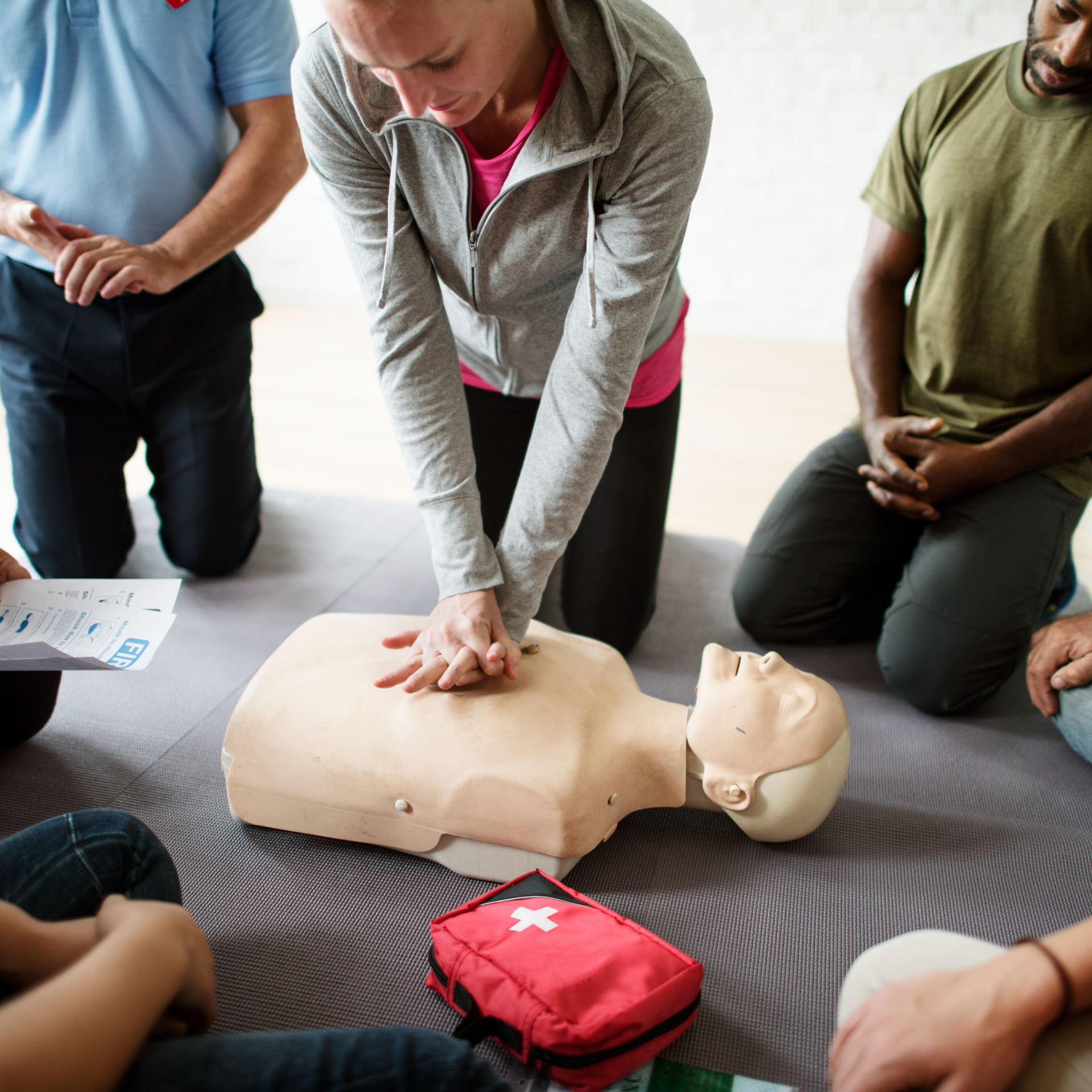Photo of someone practicing cpr on a dummy while other people watch