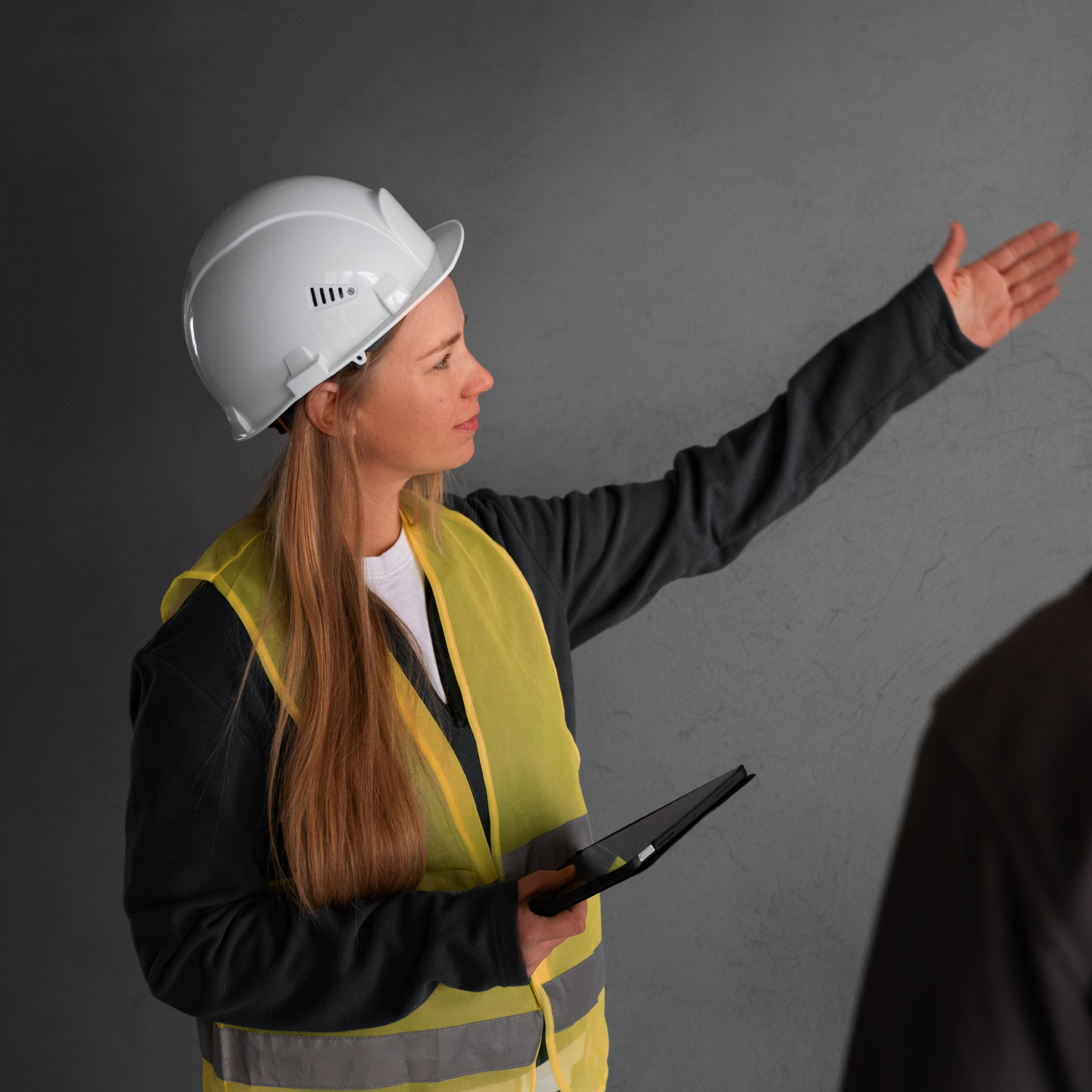 Woman wearing a hard hat and high vis pointing
