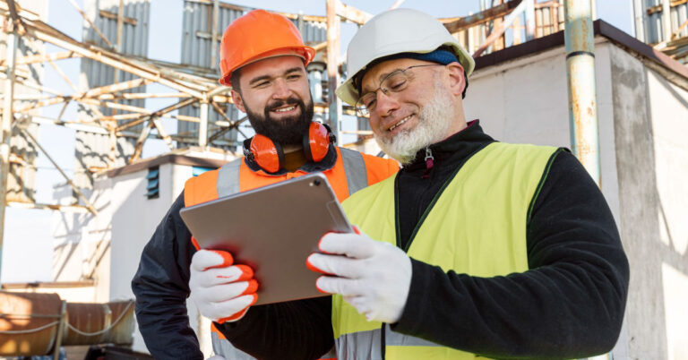 Photo of two construction workers looking at an ipad