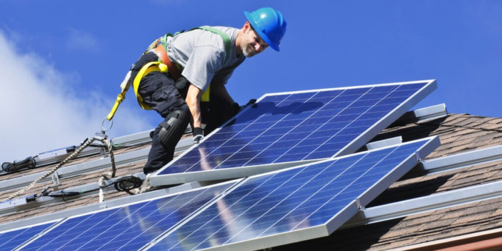 Photo of a construction worker on a roof installing solar panels