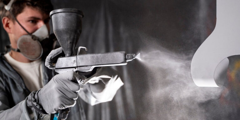 Photo of a man using a spray gun to coat an item