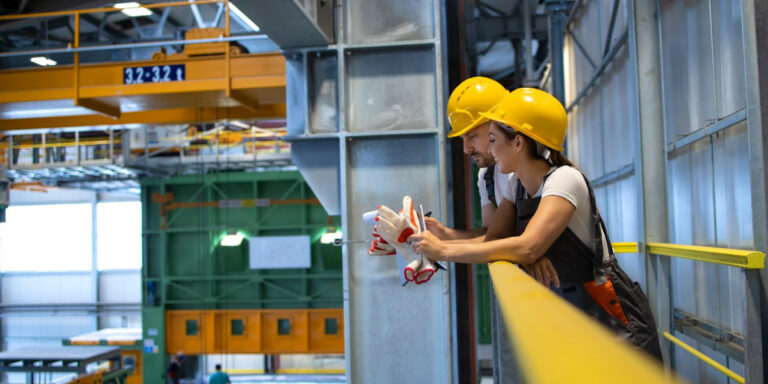 Photo of two workers wearing PPE having a conversation