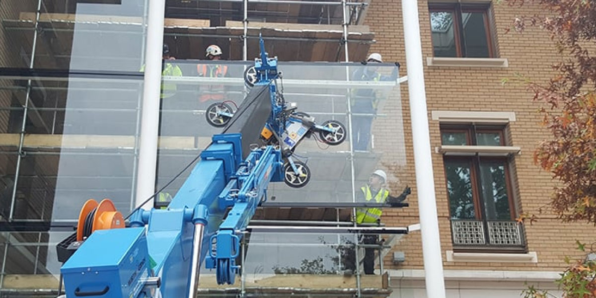 Photo of multiple construction workers using a large machine to install a big pane of glass to a building