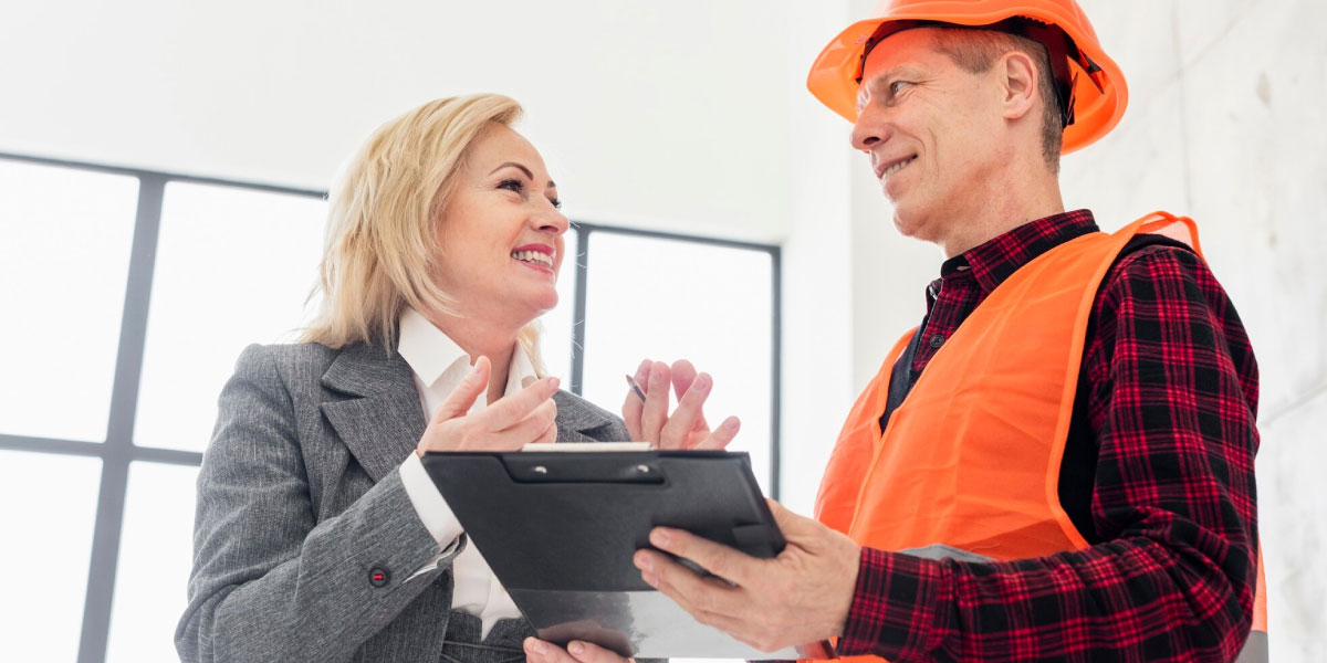 Photo of two construction workers talking and looking at a clip board