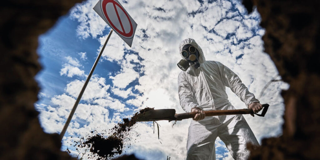 Worker wearing full PPE digging a hole