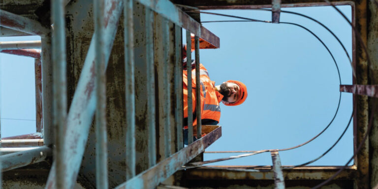 Photo of a man wearing PPE looking down a ladder