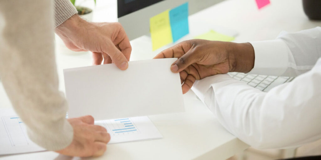 Photo of someone handing an envelope to another person