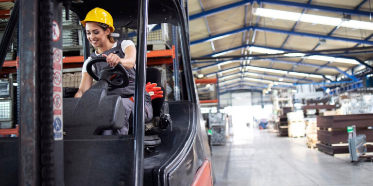 Photo of a woman operating a forklift while wearing a hard hat