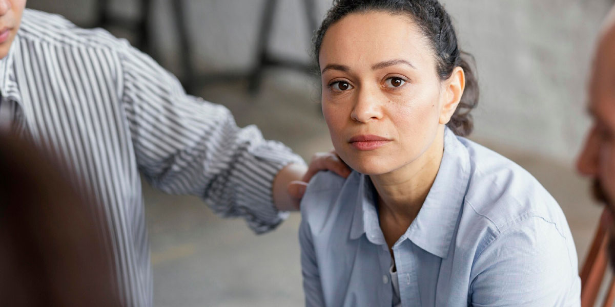 Photo of a distressed looking woman being comforted by a colleague