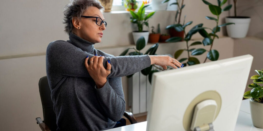 Photo of a worker sat at a desk doing stretches with their arms