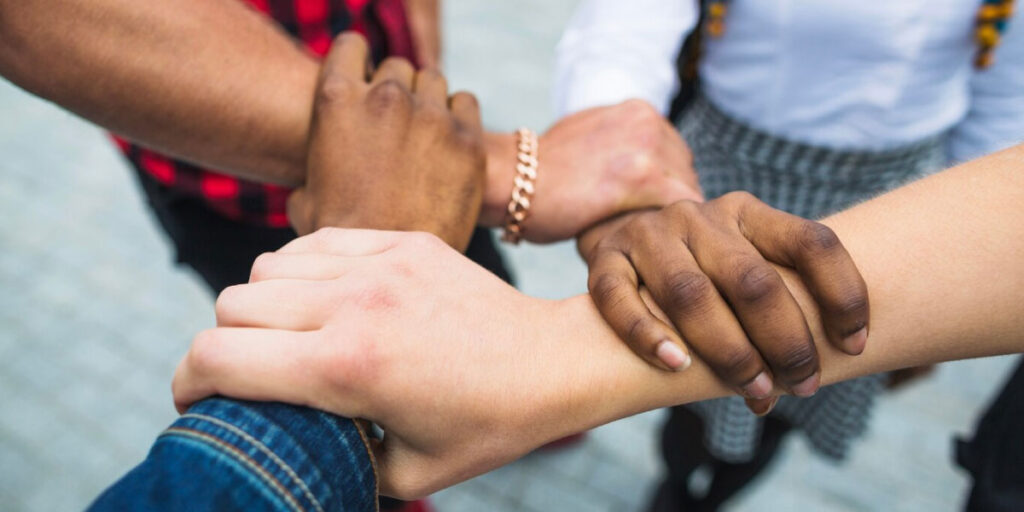 Photo of four people holding arms in an interlocking fashion