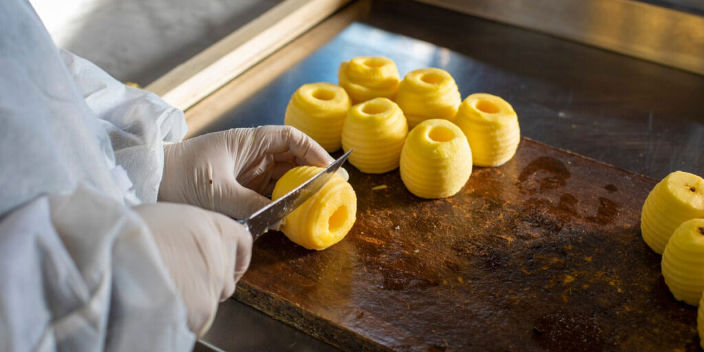 Photo of a worker cutting fruit while wearing PPE