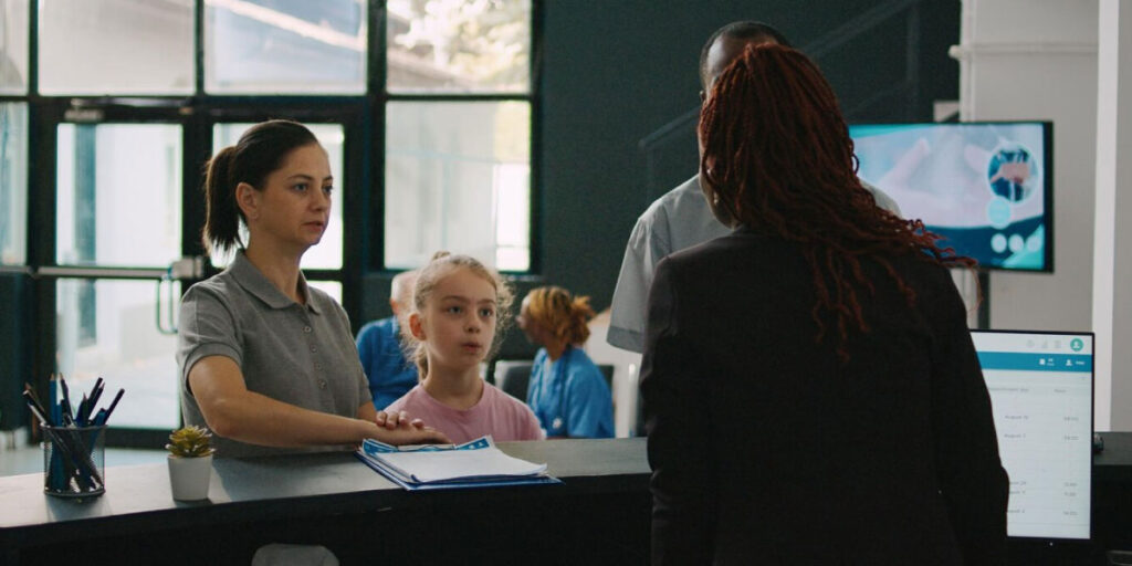 Photo of a parent with their child speaking to a reception worker