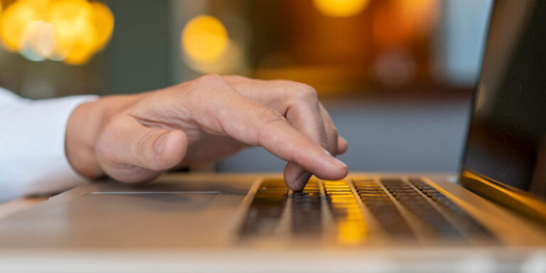 Photo of a man typing on a laptop