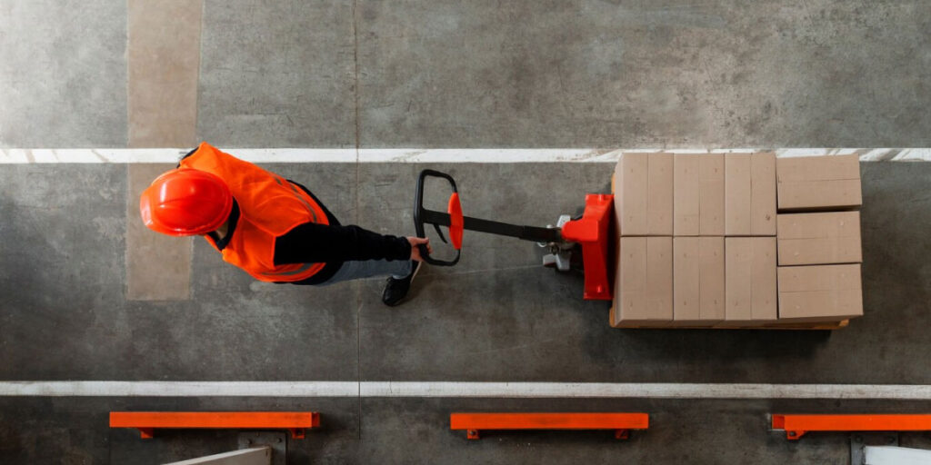 Photo of a man moving boxes using a pump truck.