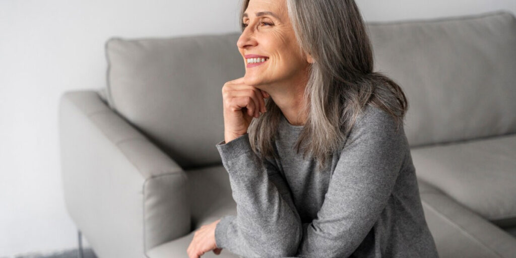 Photo of a woman sat on a couch smiling