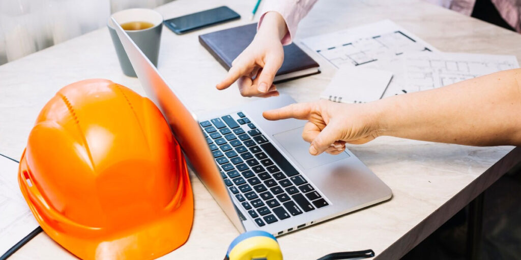 Photo of two construction workers pointing at a laptop screen