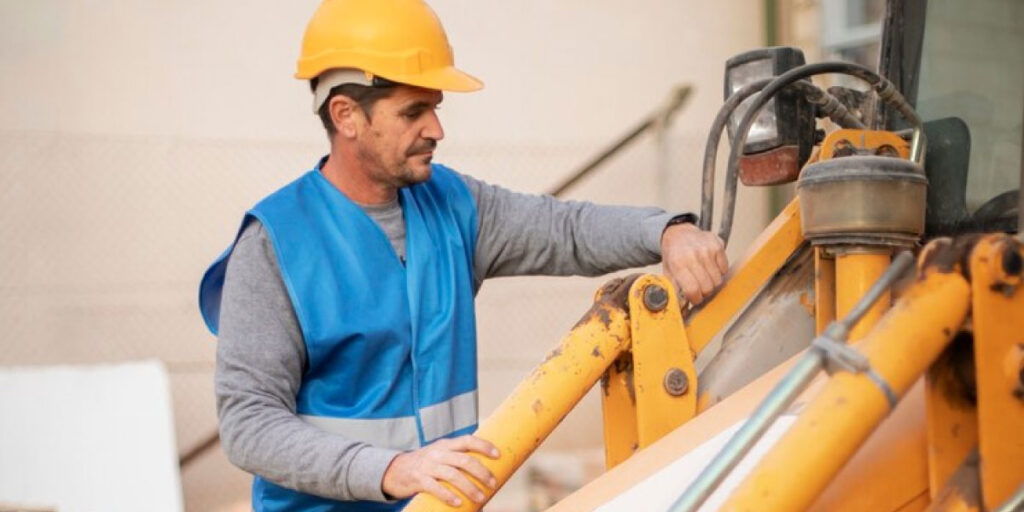 Photo of a construction worker wearing PPE working on machinery