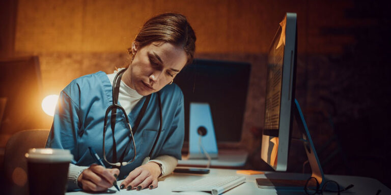 Photo of a worker sat doing work on a computer at night