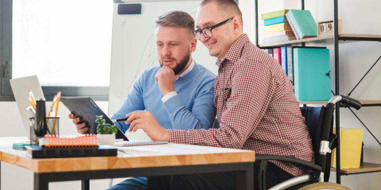 Photo of a man in a wheelchair talking to another employee in the office