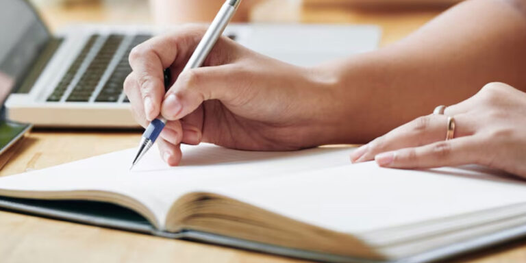 Photo of a person writing into a notebook