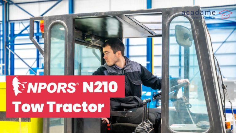 NPORS tow tractor training course image showing a tow tractor operator driving in an industrial warehouse or production environment
